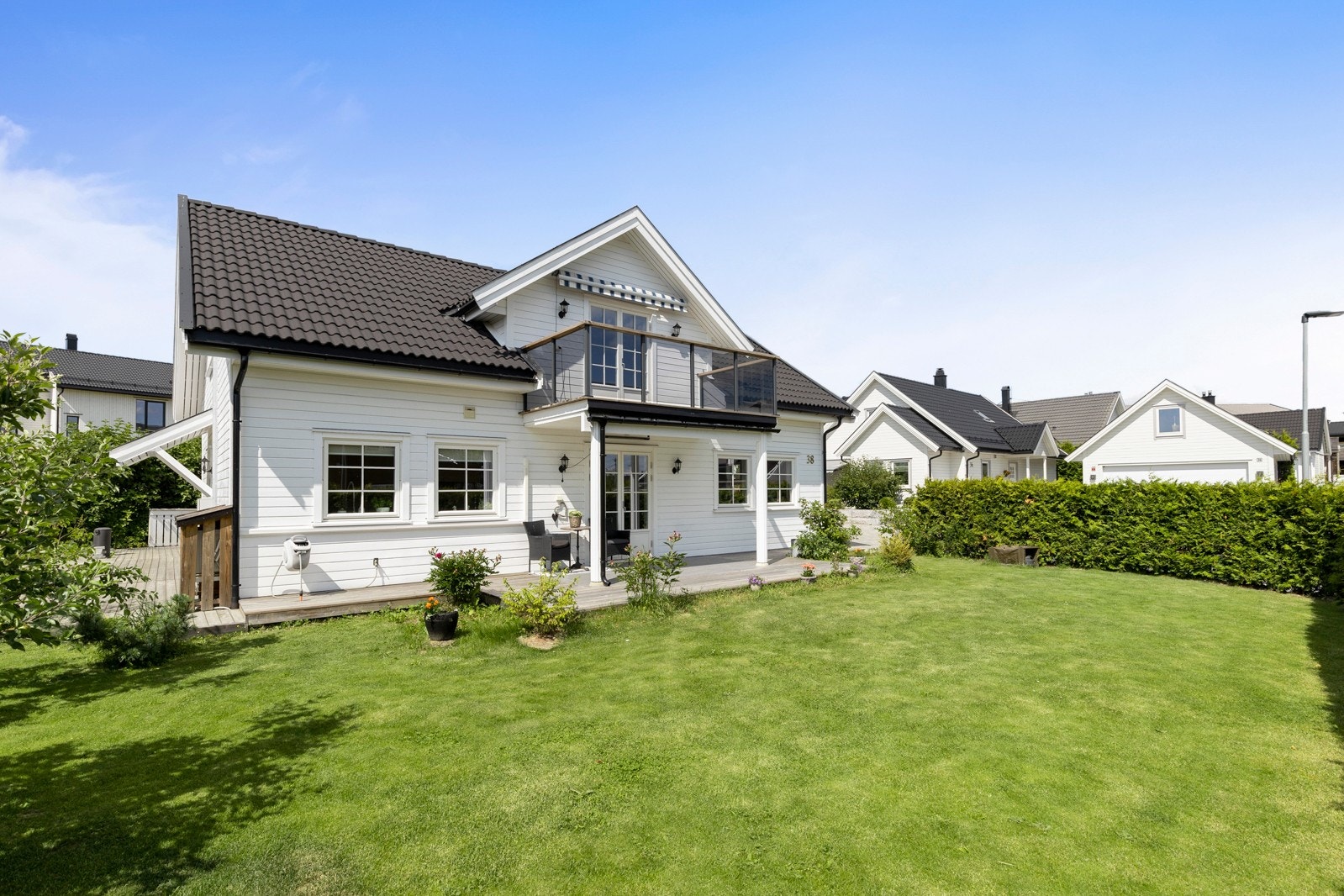 Eiendommen byr på stor gressplen, pent innrammet med hekk som begrenser innsyn Galleribilde