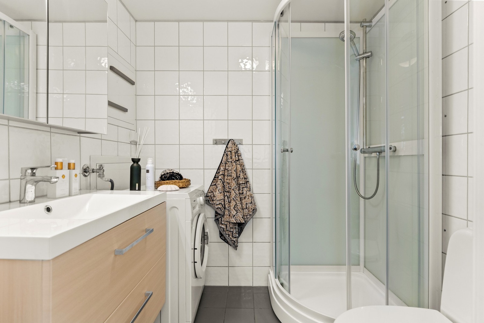 Badet er flislagt med varmekabler, opplegg til vaskemaskin, dusj, toalett og vaskeservant med skap. Galleribilde