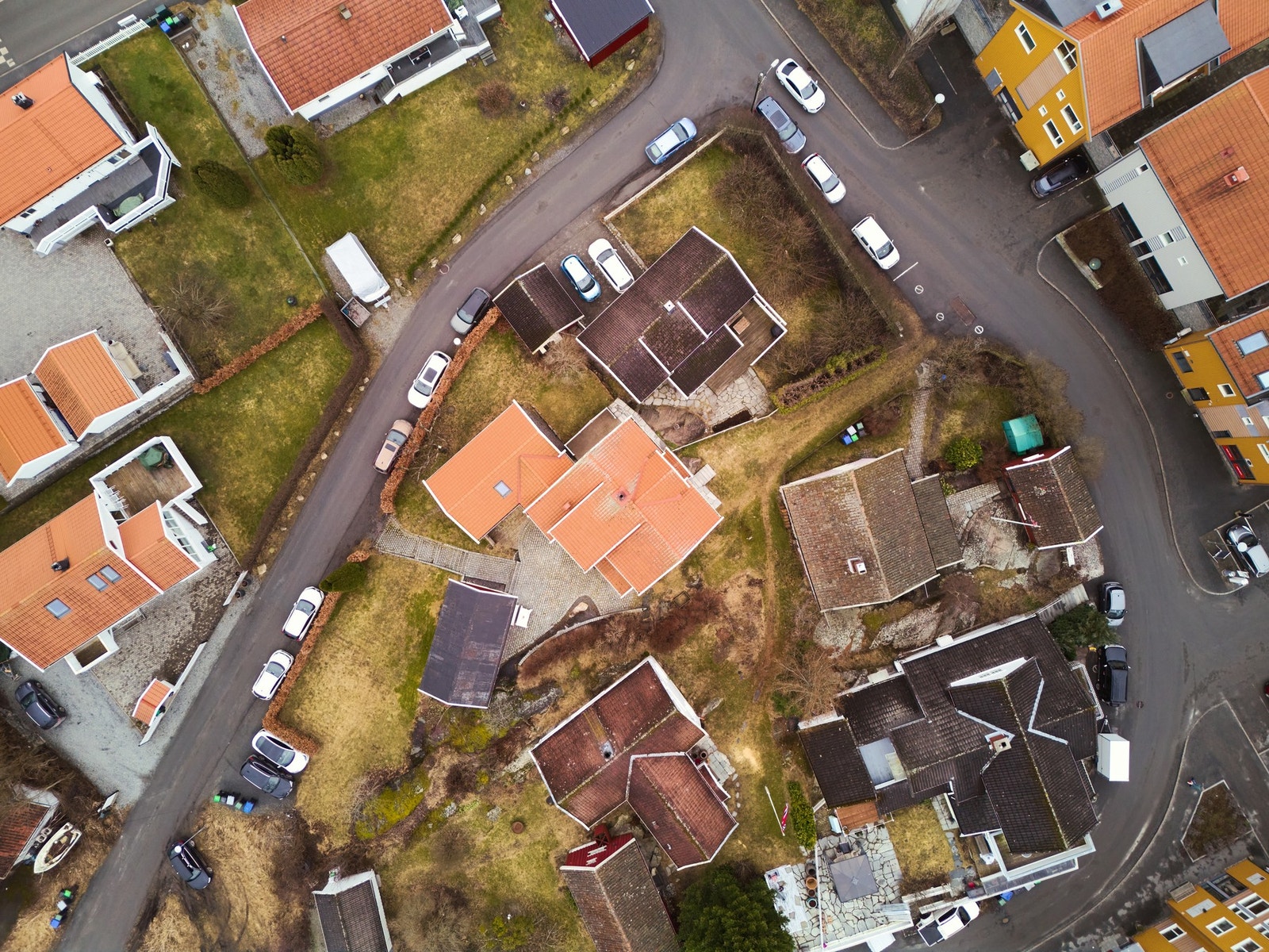 Oversiktsbilde av eiendommen. Stor hage på nedsiden av uthuset med biloppstillingsplasser og elbil-lader. Galleribilde