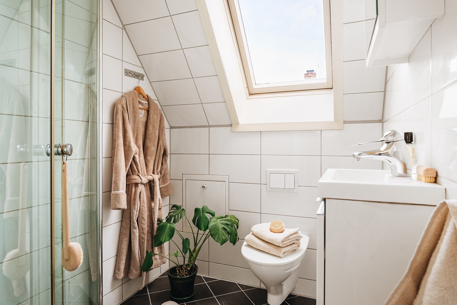 Badet er innredet med servant med skap, veggmontert toalett og dusjvegger/hjørne. Galleribilde