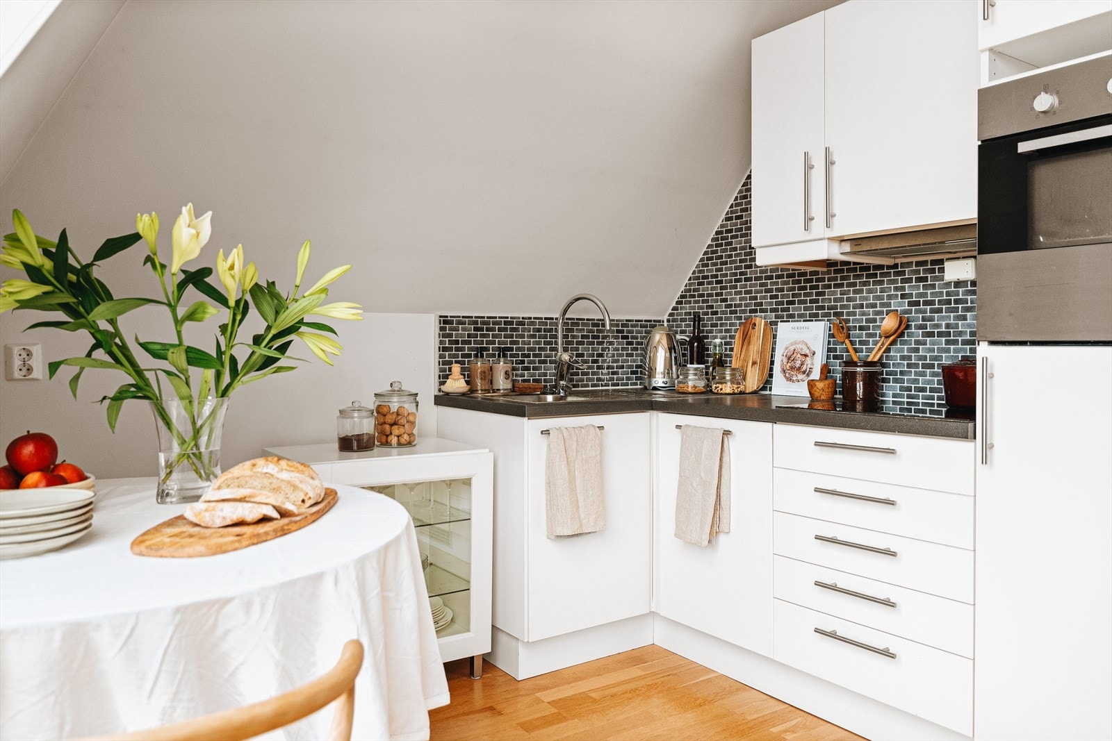 Kjøkkenet er innredet med glatte fronter og benkeplate av laminat. Over benkeplatene er det fliser. Galleribilde