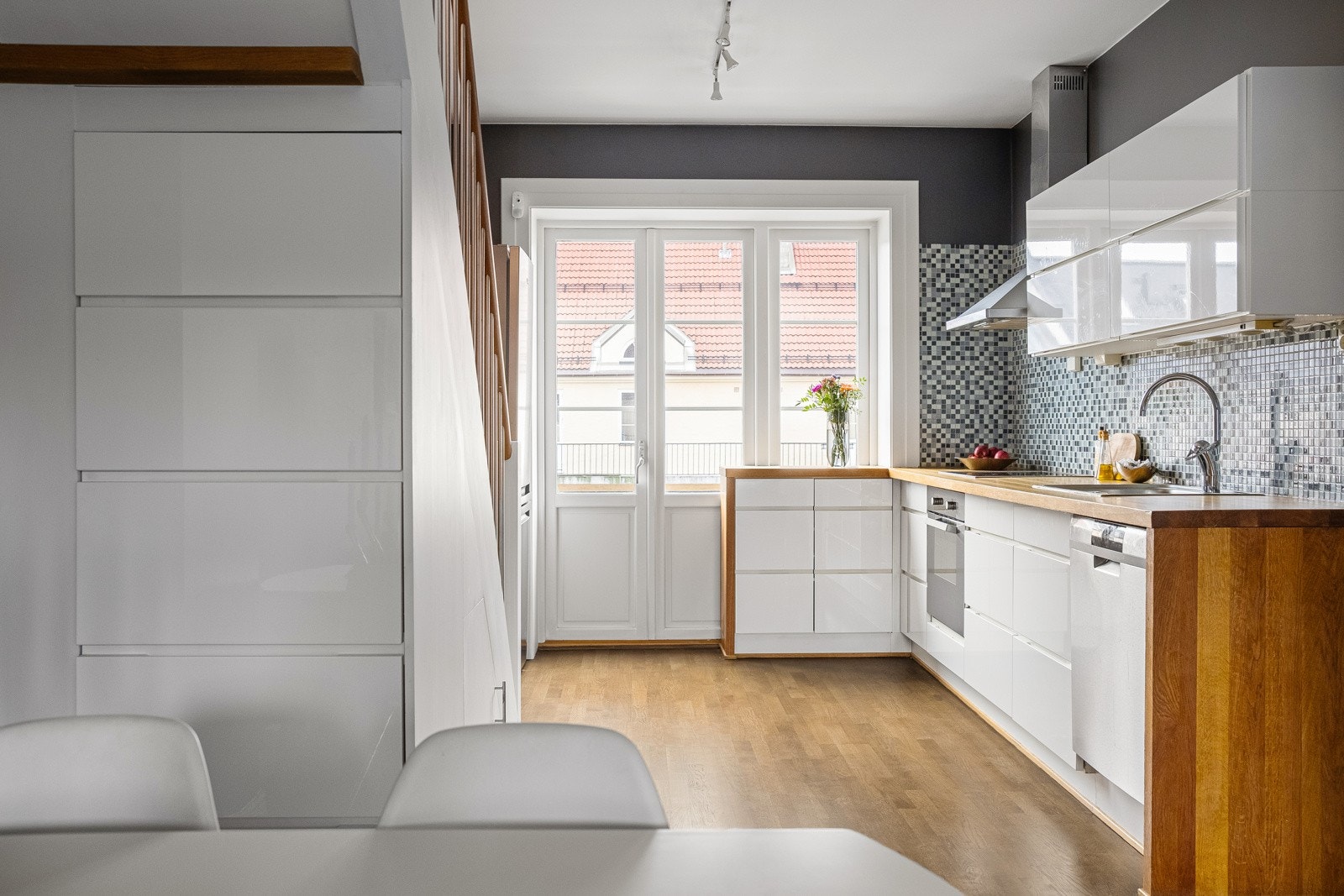 4. et: Moderne kjøkkeninnredning fra 2007 med hvite glatte fronter, heltre benkeplate og mosaikkfliser/belysning mellom over- og underskap. Galleribilde