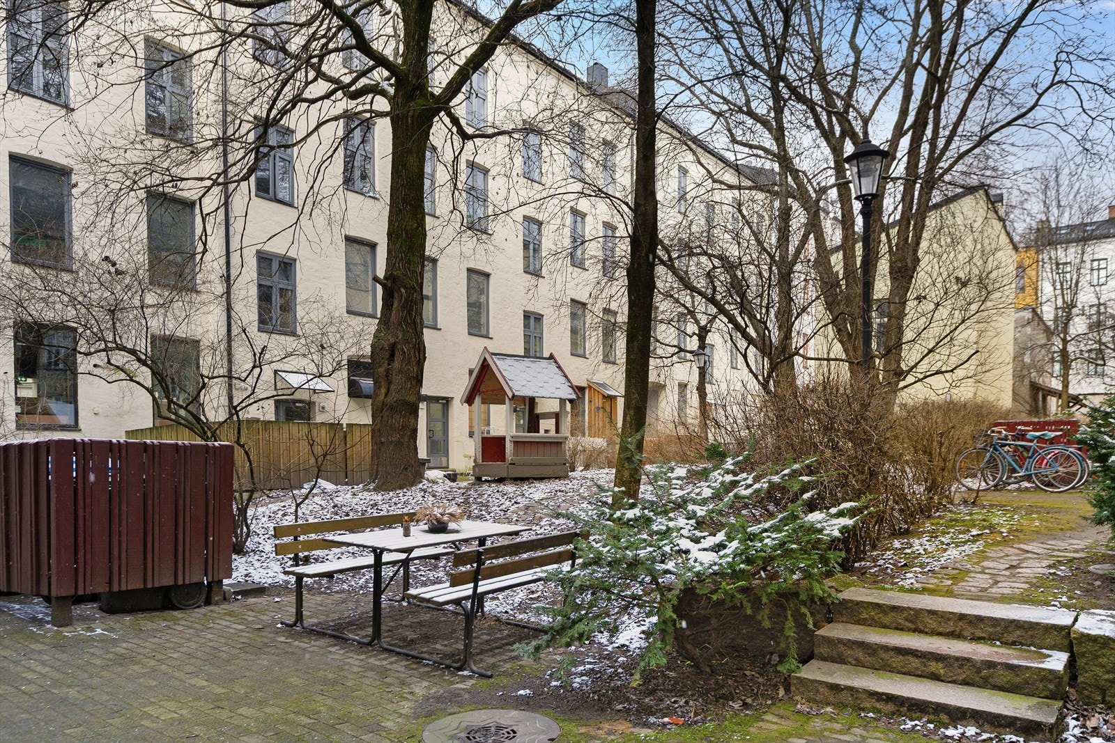Pen, frodig og innbydende bakgård med belegningsstein, sittegrupper, heller og prydbusker. Bakgården er et perfekt tilholdssted på varme sommerdager Galleribilde