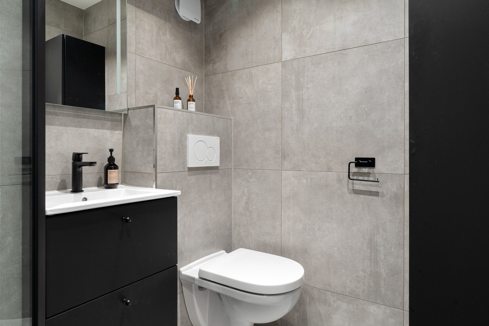 Badet er innredet med vegghengt toalett, servant, speil med integrert lys og downlights. Galleribilde