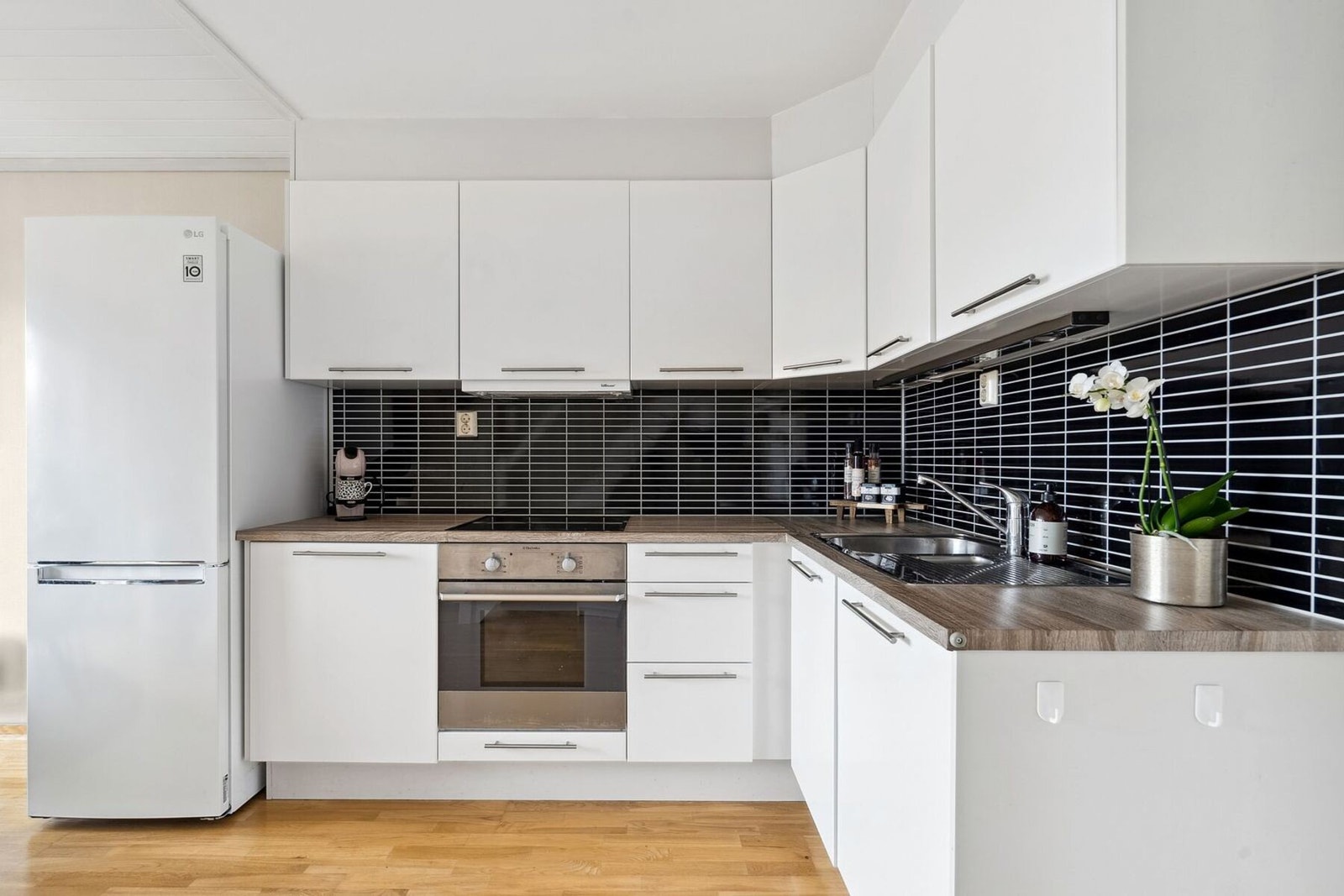 Lyst og fint kjøkken med lakkerte fronter og integrert vaskemaskin Galleribilde