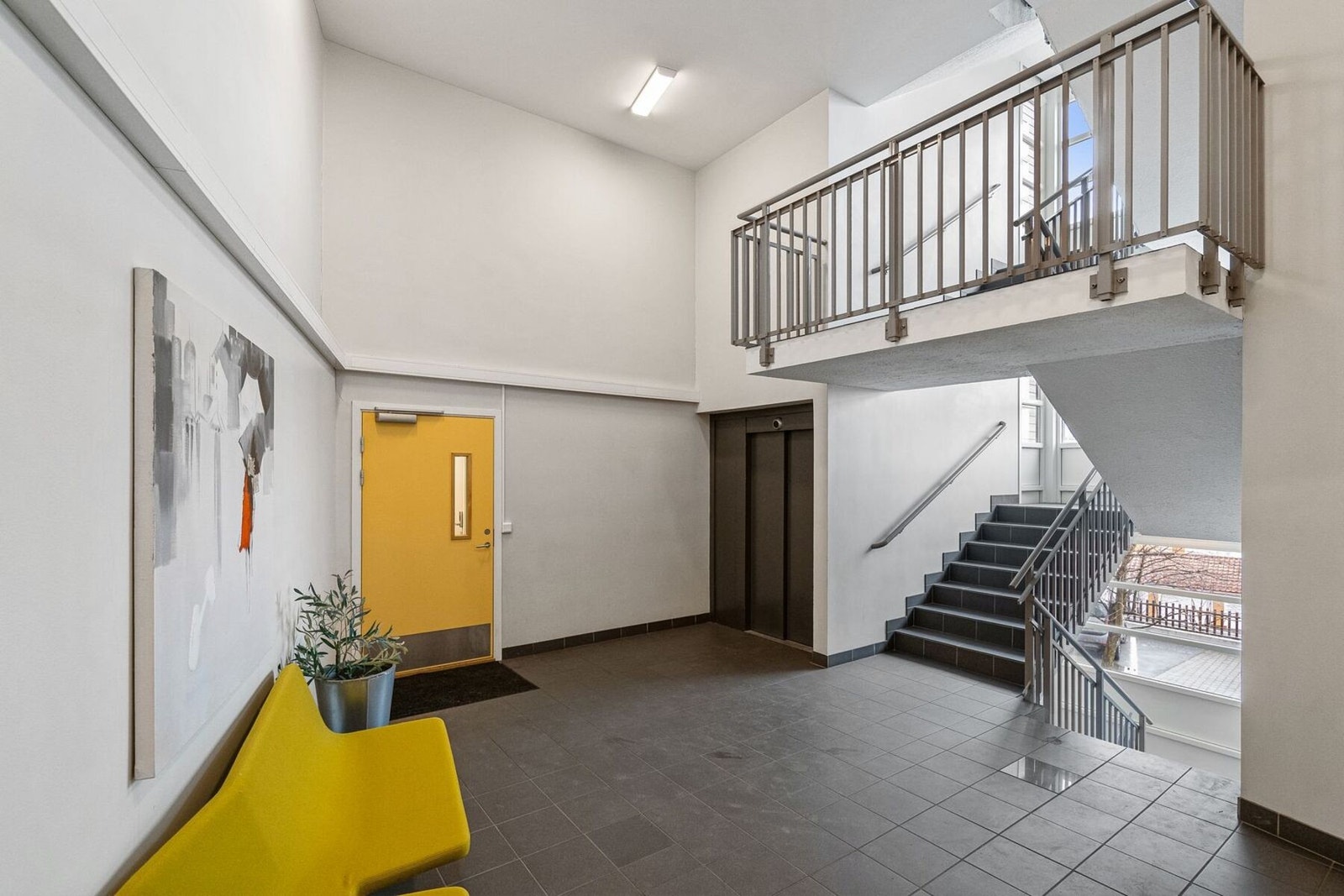 Romslig fellesgang med trapp og heis opp til leiligheten Galleribilde