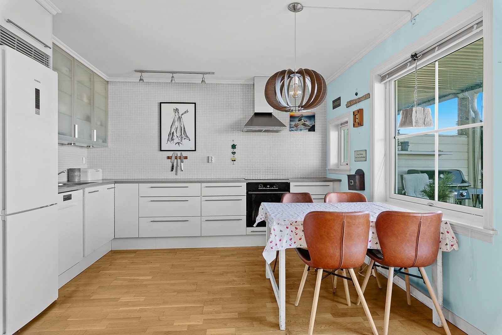 Kjøkkeninnredning med glatte fronter og laminert benkeplate. Mellom benk og overskap er det turkise, delikate mosaikk fliser. Galleribilde