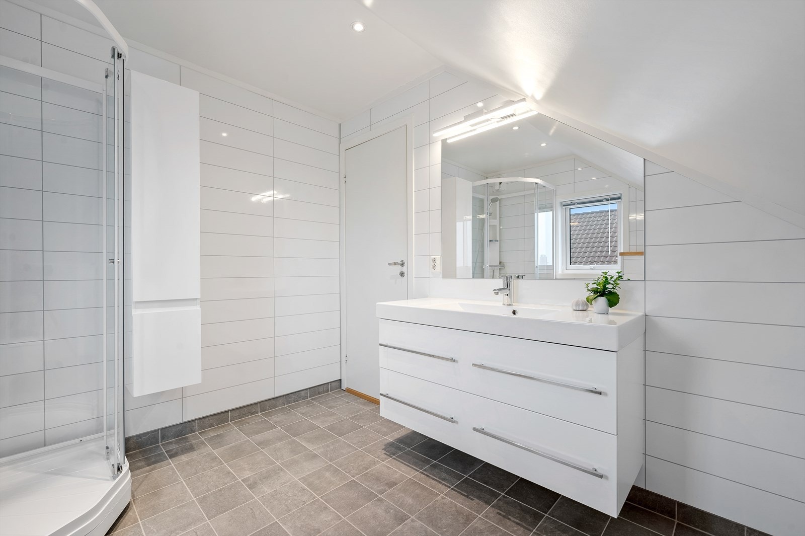 Bad innredet med servant i møblement, dusjkabinett og vegghengt toalett. Galleribilde