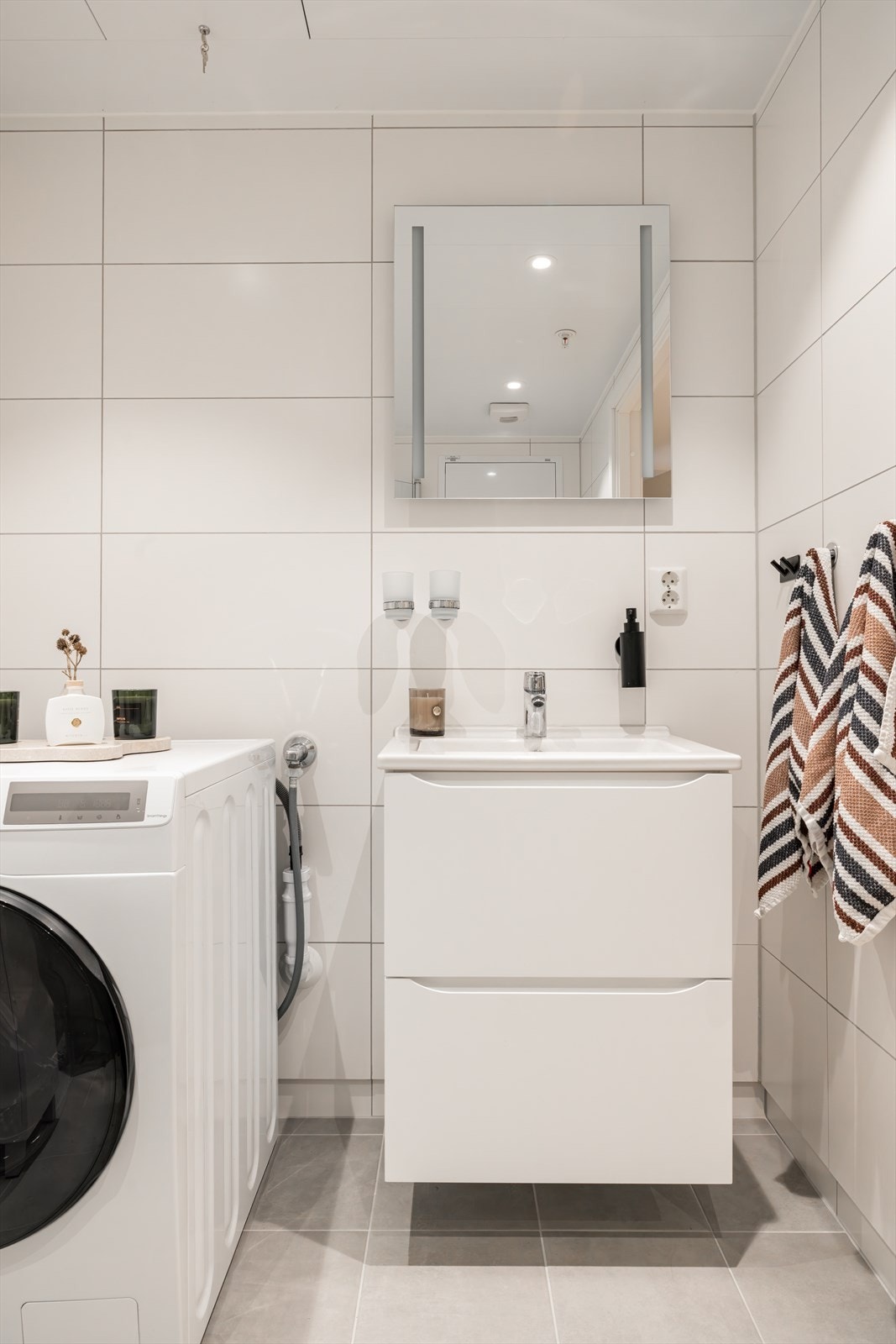 Badet har opplegg for vaskemaskin og tørketrommel i hjørnet. Galleribilde