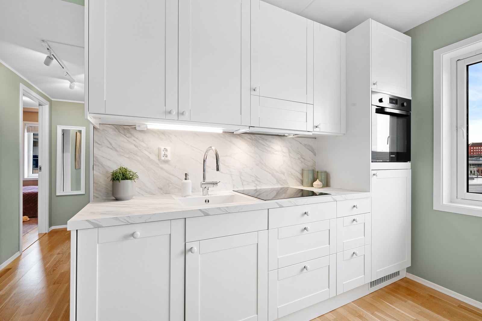 Kjøkkenet inneholder integrerte hvitevarer som platetopp, stekeovn, oppvaskmaskin og kjøleskap. Galleribilde