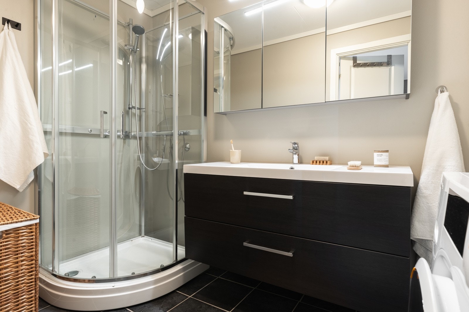 Badet er innredet med baderomsmøbel, dusjkabinett og opplegg for vaskemaskin. Galleribilde
