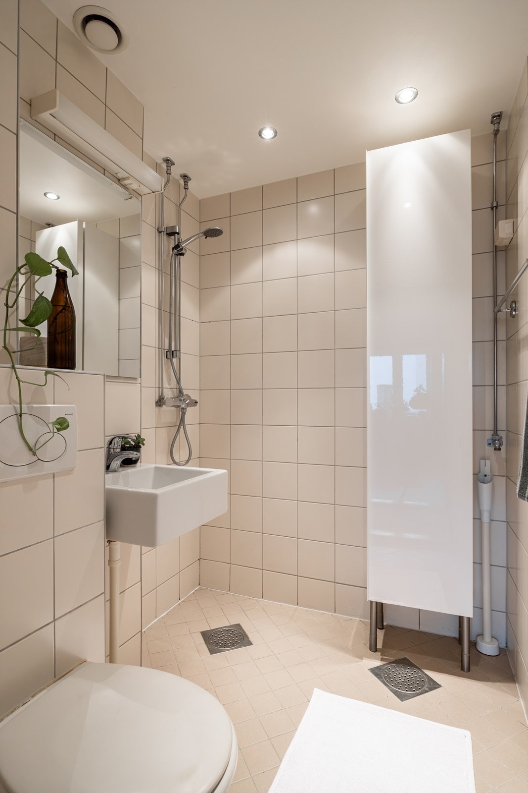 Gulvvarme, vegghengt toalett, servant og dusj. Det er opplegg til vaskemaskin i hjørnet, dersom man tar bort skapet. Galleribilde