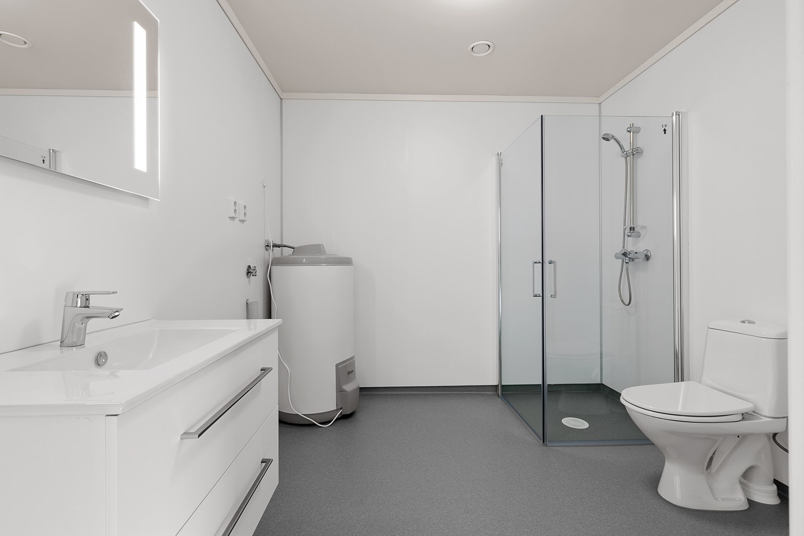 På badet er det belegg på gulv, og baderomsplater på veggene. Badet inneholder servant med skap, et pent led speil og dusjhjørne. Galleribilde