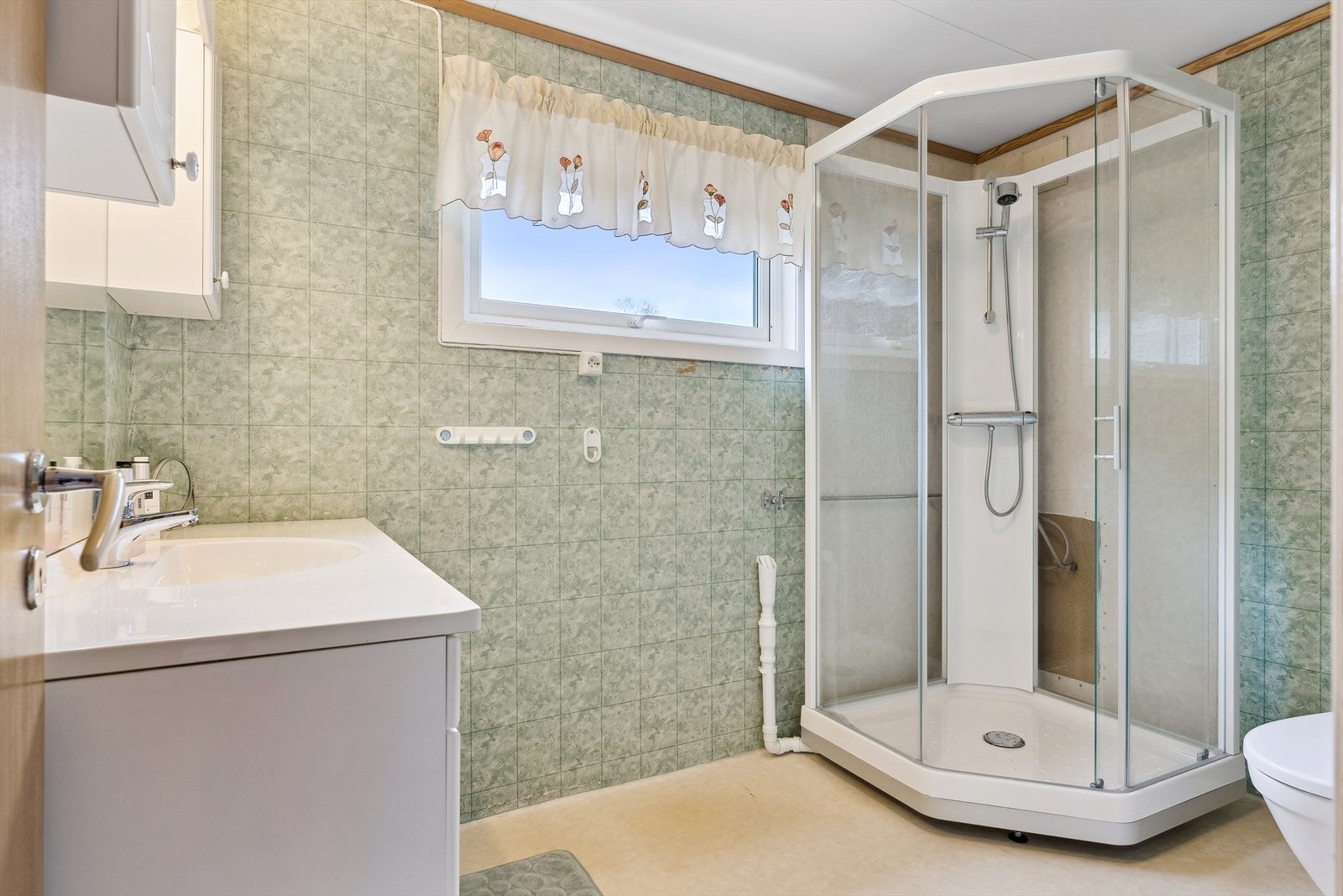 Baderom med våtromstapet/belegg. Varmekabler i gulv. Inneholder ellers servant med skap, wc, dusj og tilkobling vaskemaskin. Galleribilde