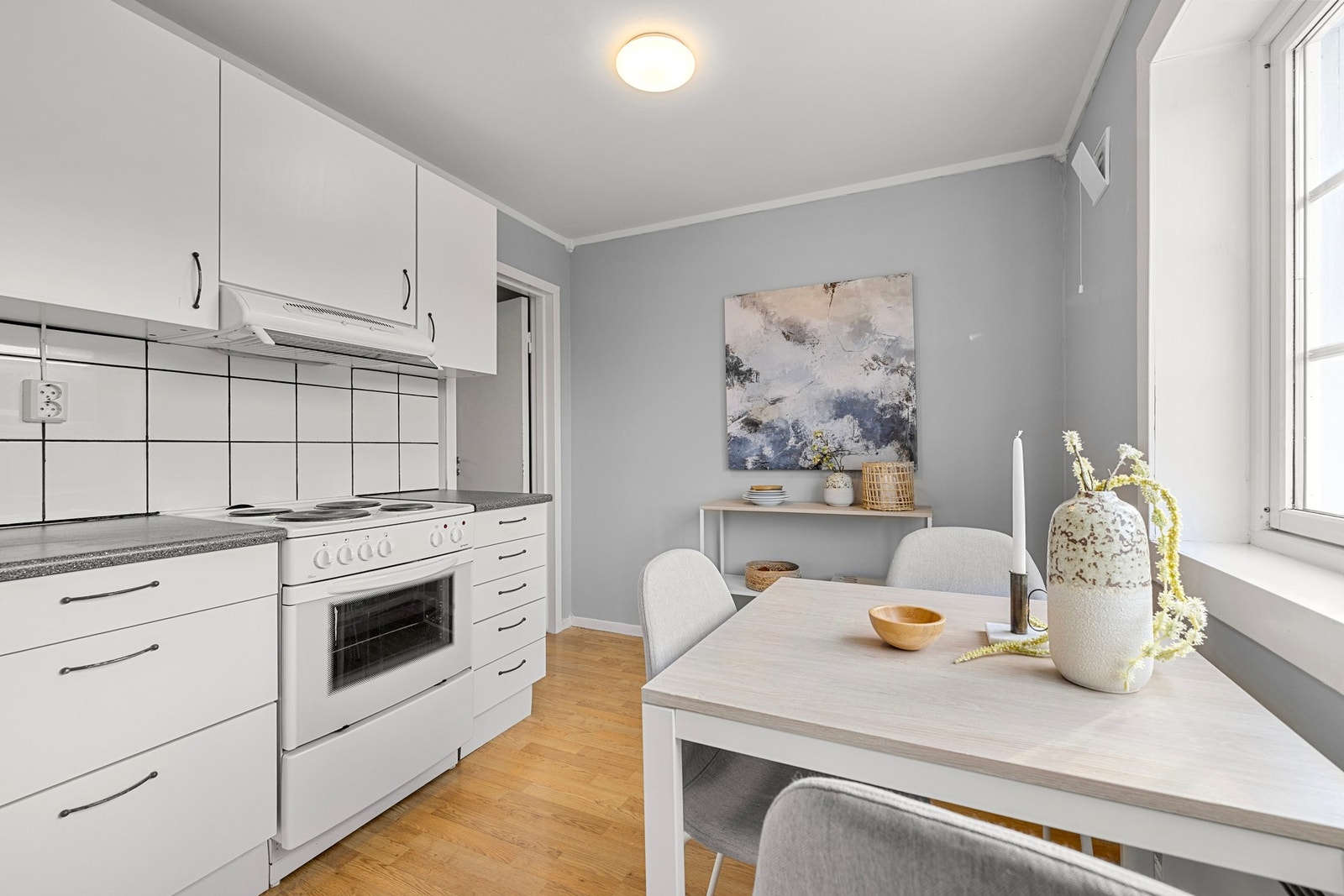 Hvite kjøkkenfronter kombinert med fliser og lyse overflater skaper et rent uttrykk. Galleribilde