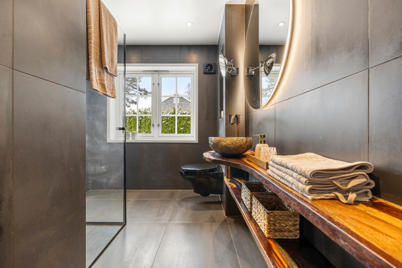 Et eksklusivt bad med store, mørke fliser og stilrene detaljer. Galleribilde