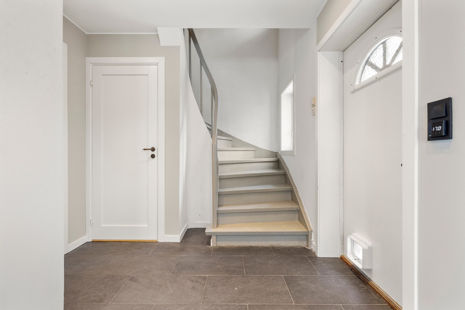 En innbydende inngang med moderne grå fliser og en klassisk trappeløsning. Galleribilde