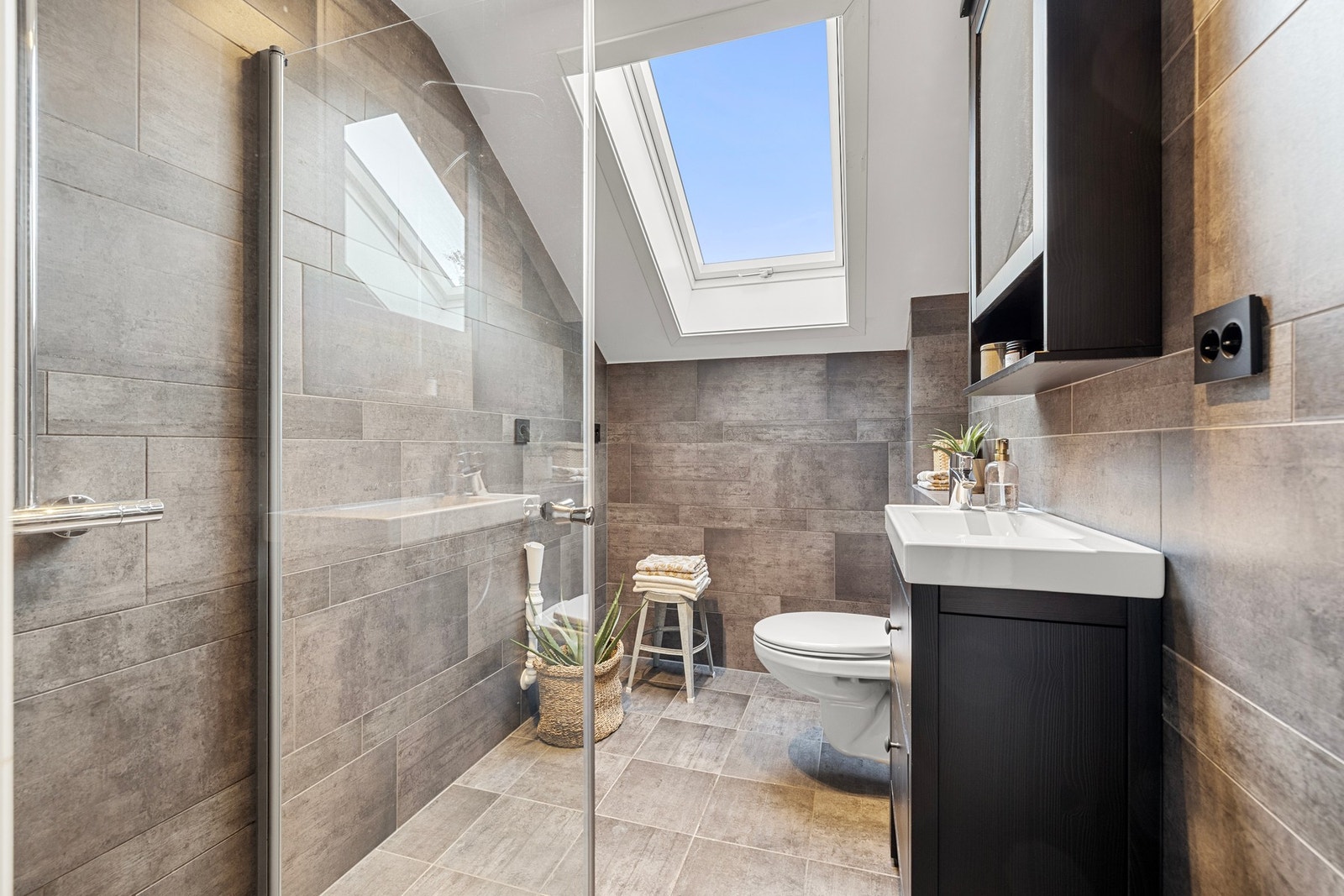 Et elegant bad med store fliser og delikate detaljer. Takvinduet slipper inn masse dagslys. Galleribilde