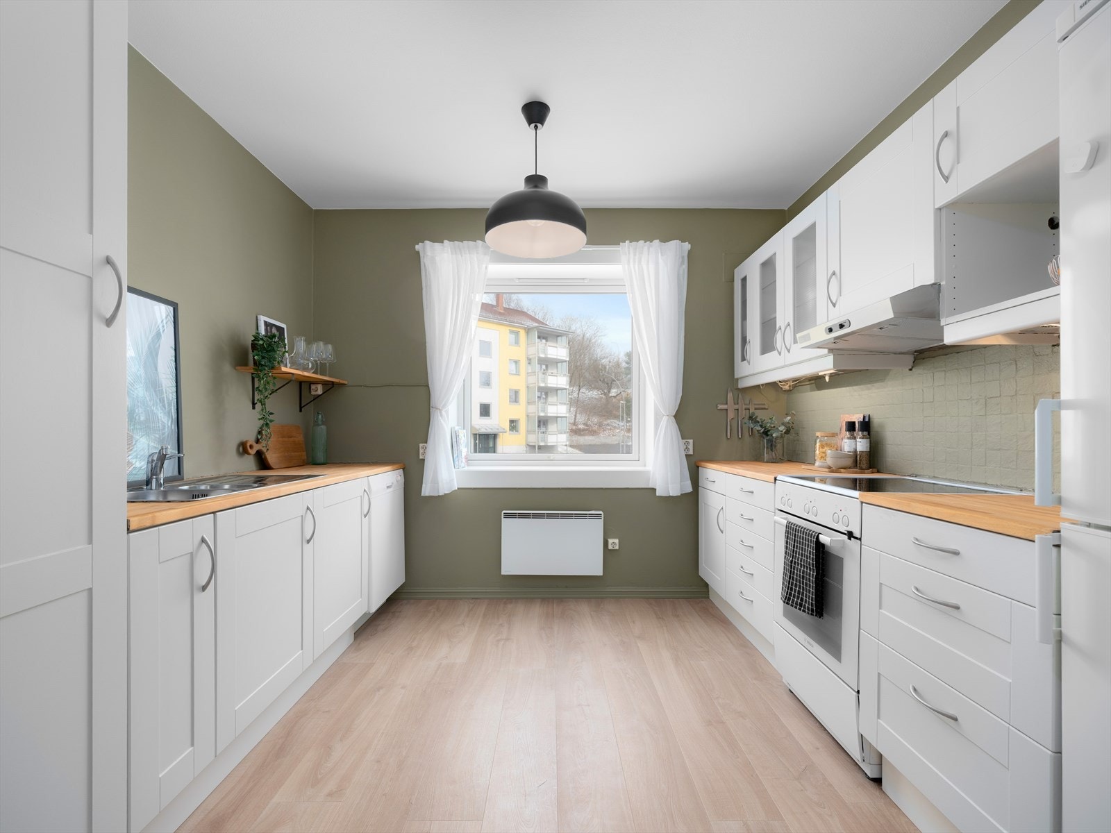 Kjøkken med hvite skapfronter og mye benkeplass. Galleribilde