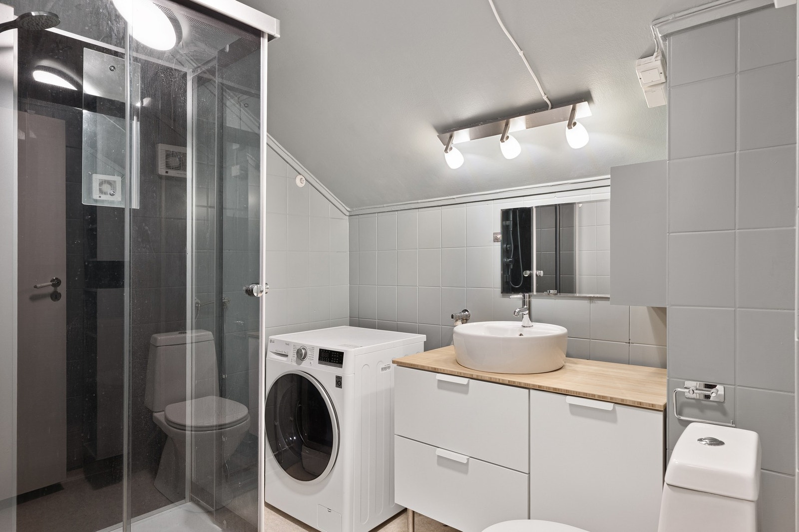 Bad med servant, toalett, dusjkabinett og opplegg for vaskemaskin. Galleribilde