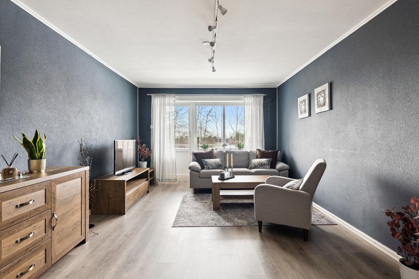 Romslig og lun stue med vinduer og dør ut mot balkonge. Vinduer og balkongdør er skiftet i regi av brl. i 2013. Galleribilde