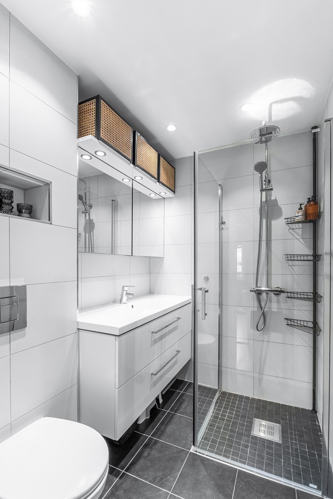 Meget pent flislagt bad med gulvvarme. Badet har dusjhjørne med dører i herdet glass, veggfestet klosett og overskap med speilfronter. Galleribilde