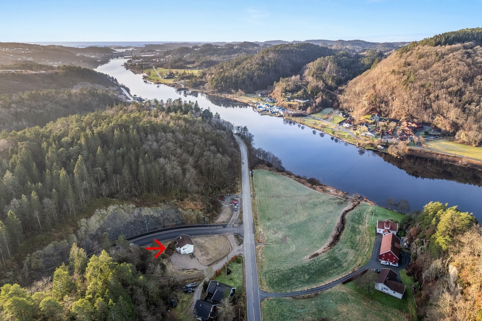 Dronebilde. Tomten er på ca 27 mål og strekker seg fra heia bak boligen og ned til elva. Lang strandlinje. Galleribilde