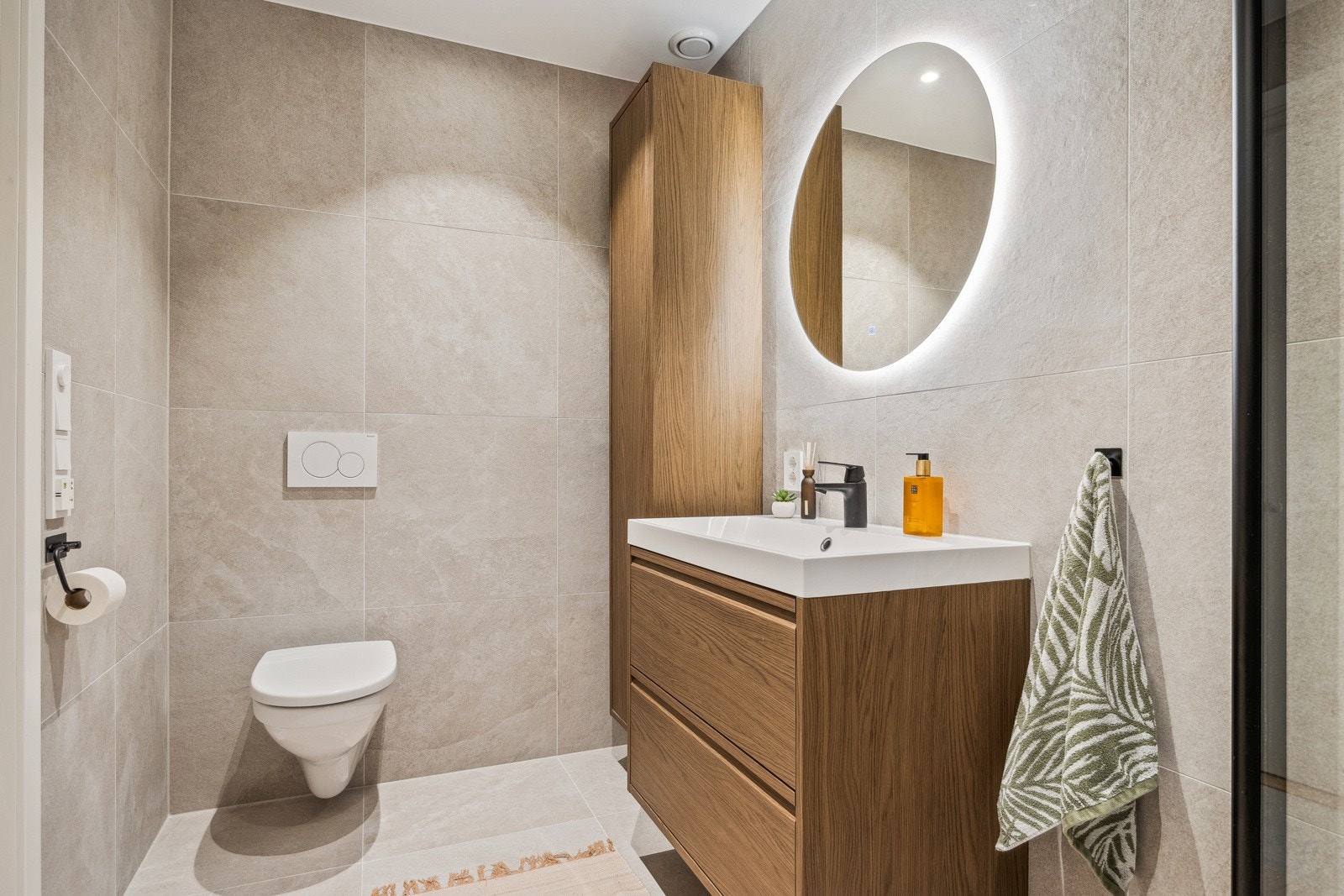 Det 5 kvm store badet er innredet med lyse, stilrene fliser for et rent og luksuriøst uttrykk. Den øvrige innredningen består av et vegghengt skap, servant med skuffeseksjoner og speil med integrert belysning. Badet ble oppgradert i 2024. Galleribilde