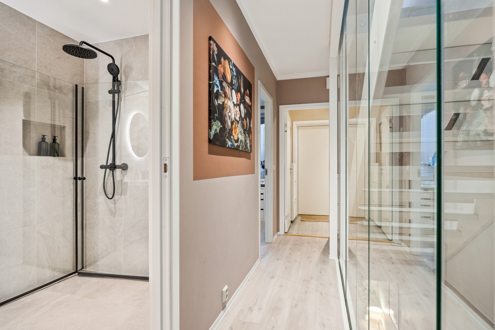 Fra entréen ankommer man et gangareal som fordeler seg til to soverom, baderom, samt trappeløp til øvrige etasjer. Trappen er utført med stilfull glassvegg som gir et moderne uttrykk som er gjennomgående i alle etasjer. Galleribilde