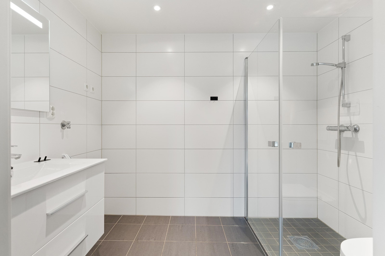 Pent flislagt bad med opplegg for vaskemaskin og tørketrommel. På badet er det vegghengt servantskap med glatte fronter. Galleribilde