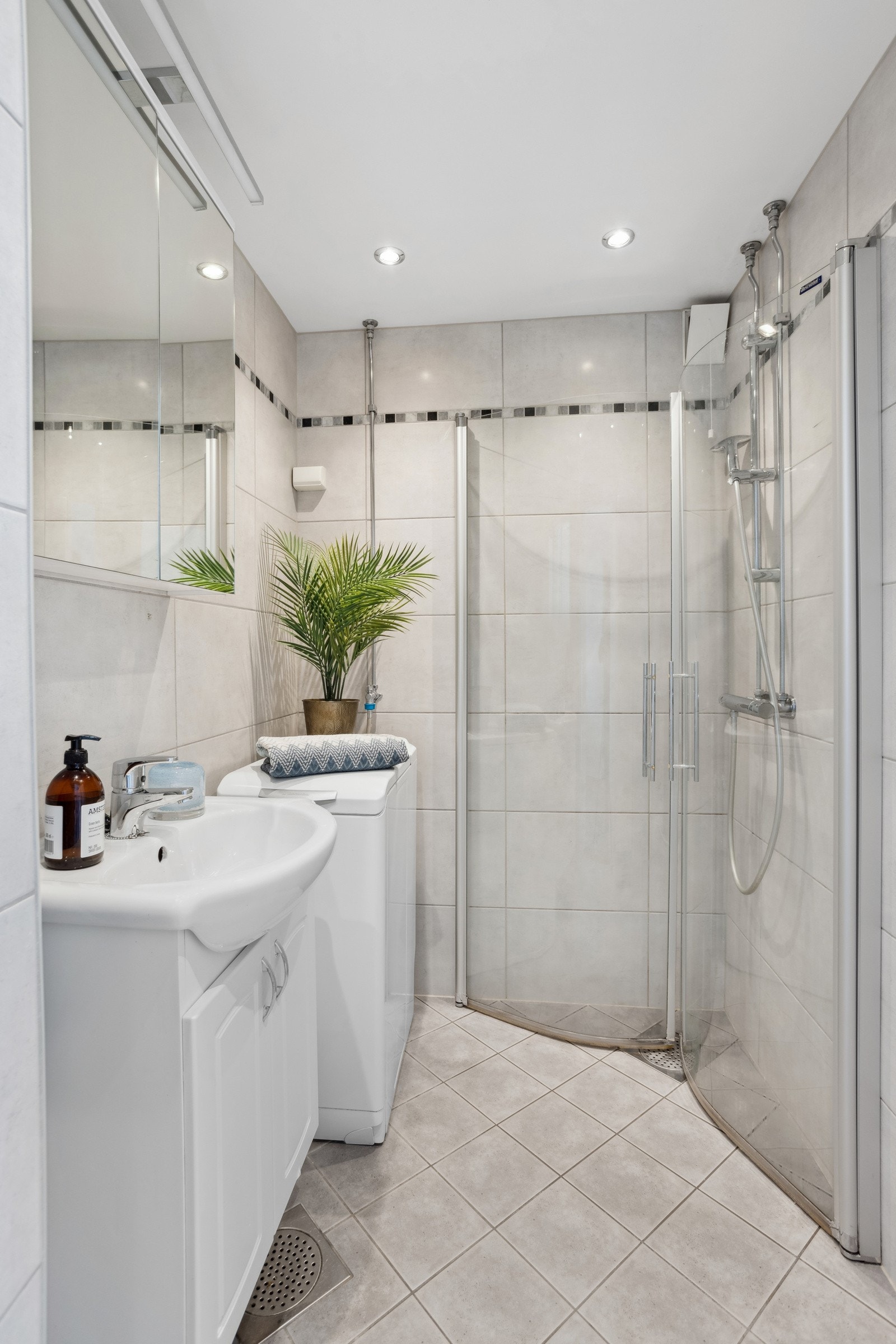 Delikat baderomsinnredning fra 2009. Består av servant med underskap, speilskap, klosett og åpen dusjløsning. Opplegg for vaskemaskin. Galleribilde