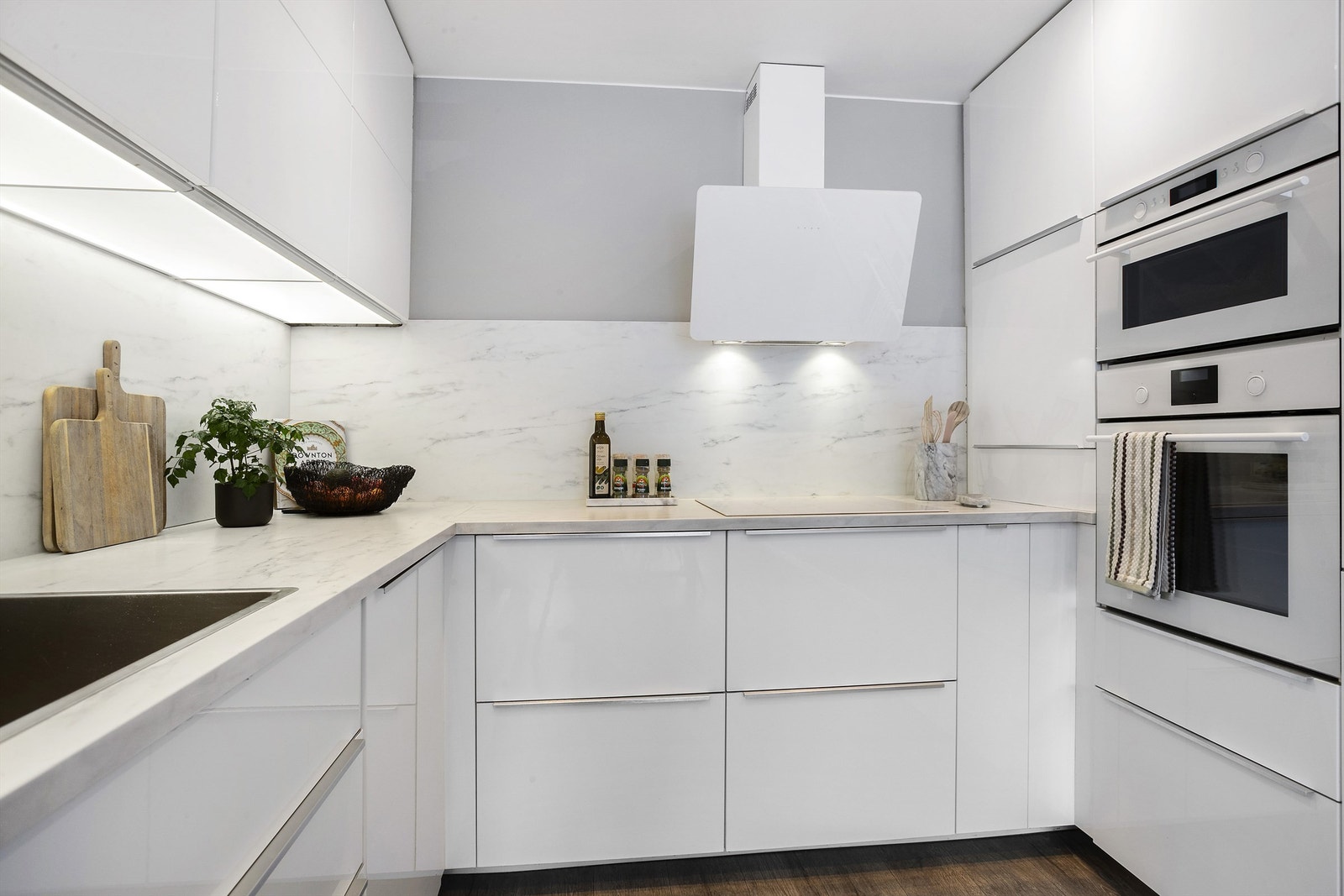 Hvit høyglans kjøkkeninnredning med laminert benkeplate og kjøkkenkum nedfelt i benkeplate Galleribilde