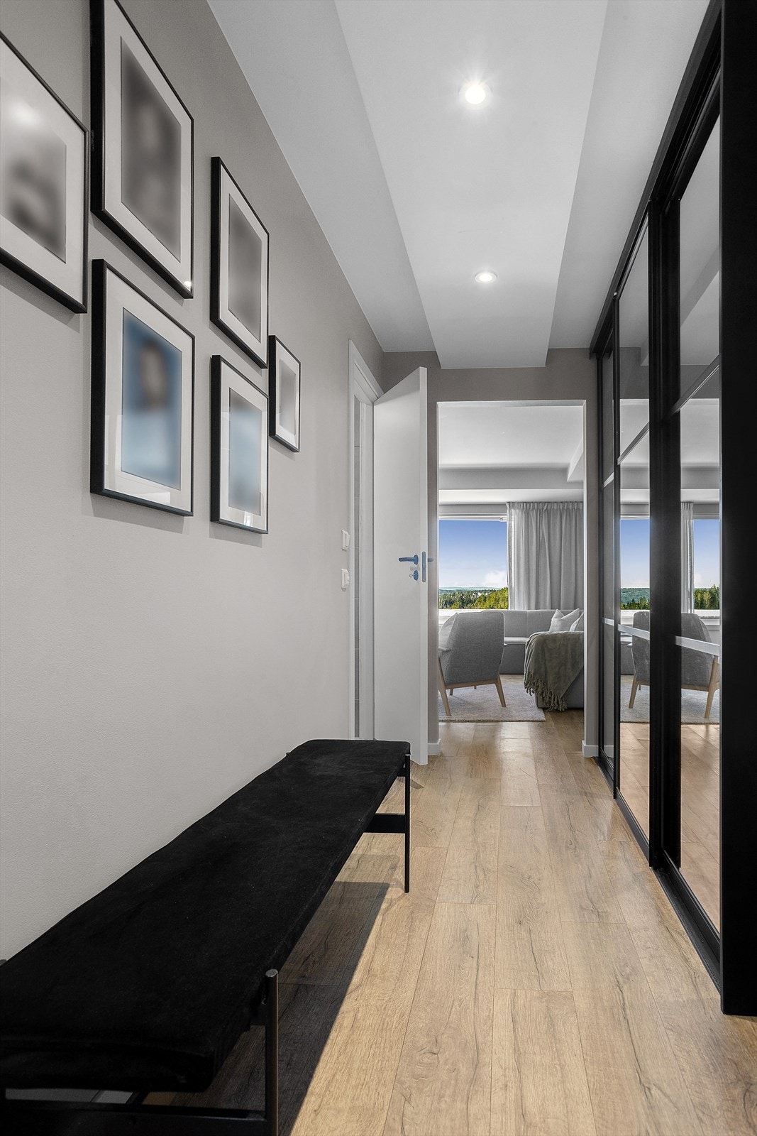 Man kommer inn i en romslig entré med klikkvinyl på gulv og skyvedørsgarderobe med speilfronter Galleribilde