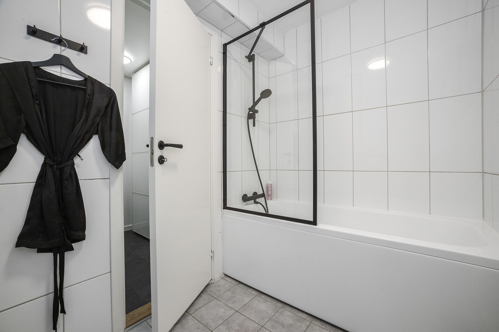 Badet har badekar, vegghengt toalett og servantskap med speil Galleribilde