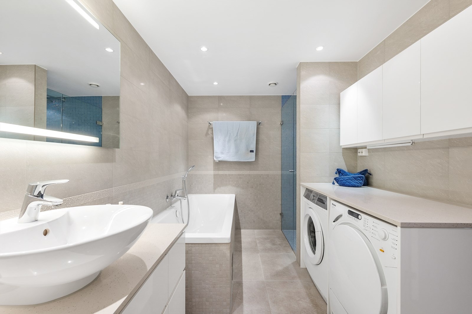 Benkeplate i kompositt med plass, samt opplegg for vaskemaskin og tørketrommel under. Gode oppbevaringsmuligheter i overskap Galleribilde