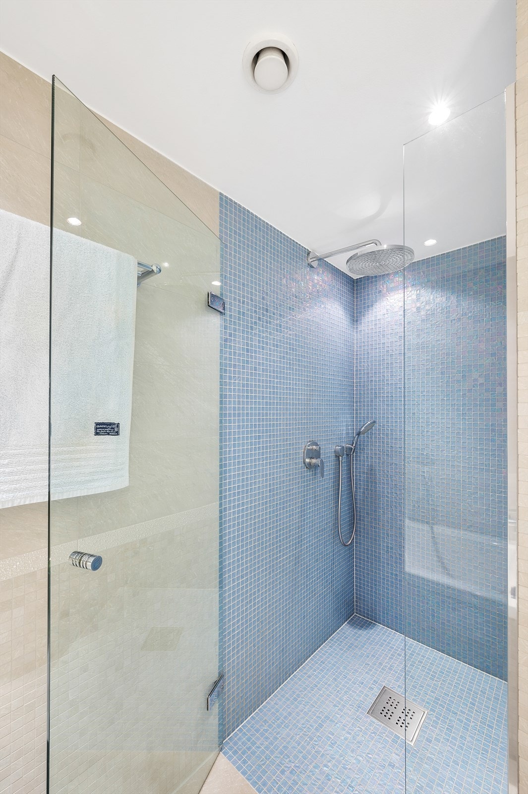 Dusjhjørne med mosaikkflis, glassdør, samt integrert armatur, hånddusj og regnfallsdusj Galleribilde