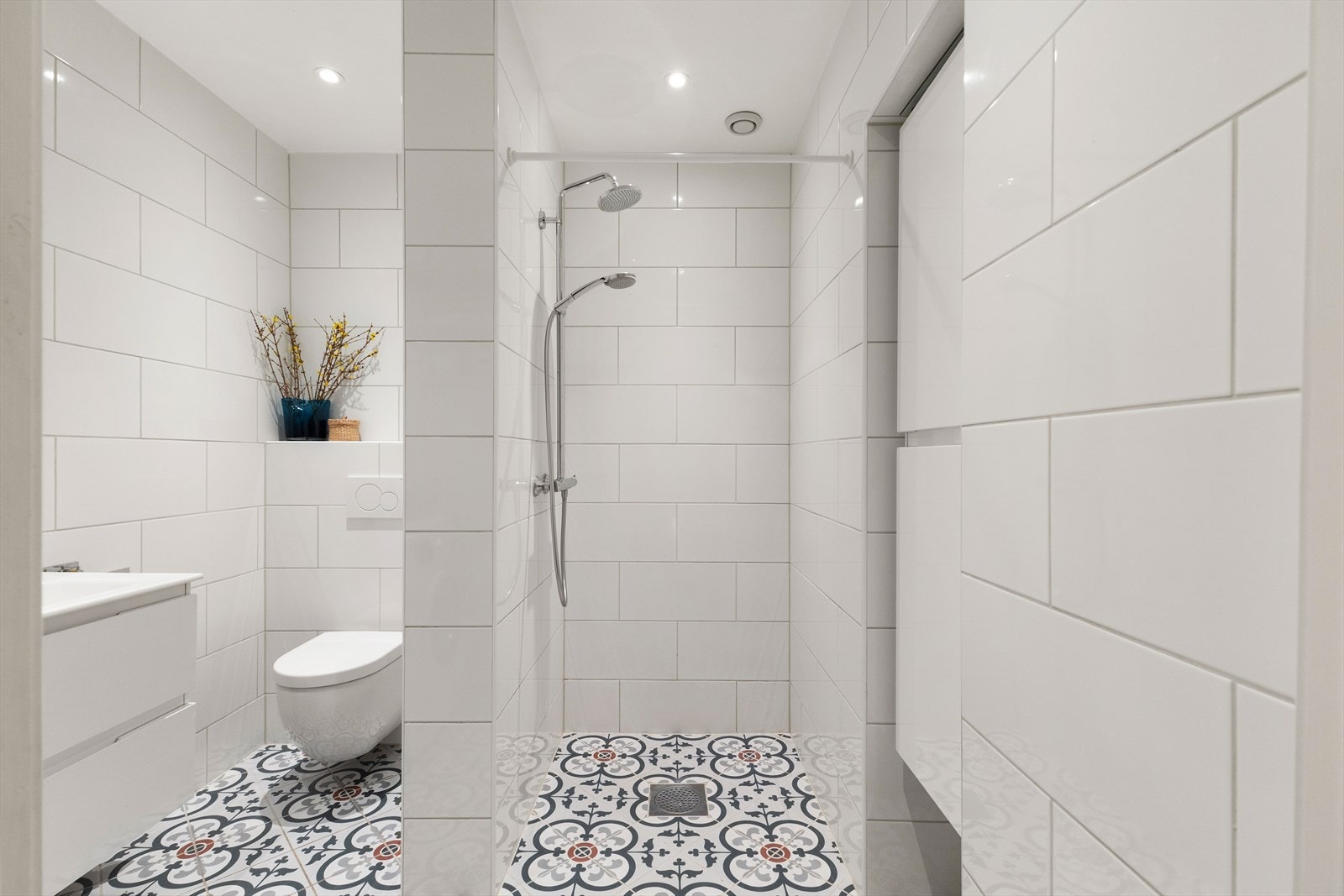 Baderommet er innredet med veggmontert klosett, servant på innredning og dusjvegger/hjørne. Galleribilde