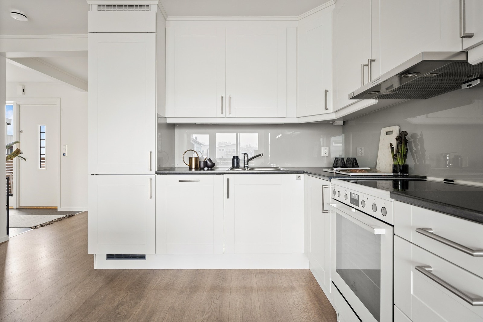 Kjøkkenet er plassert i en romslig L-form i innerste delen av stuen, noe som gir god arbeidsflyt og en sosial arbeidssone. Galleribilde