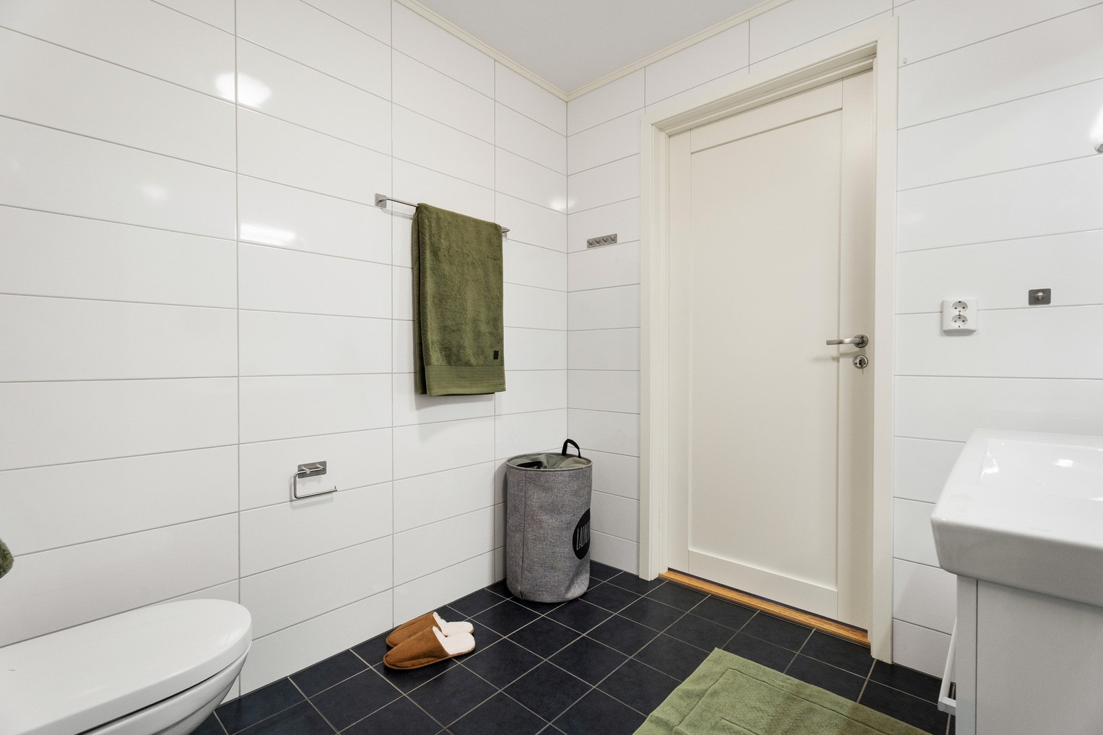 Innredningen består av en heldekkende servant på hvit skuffeseksjon, speil med overlys og et veggmontert toalett. Galleribilde