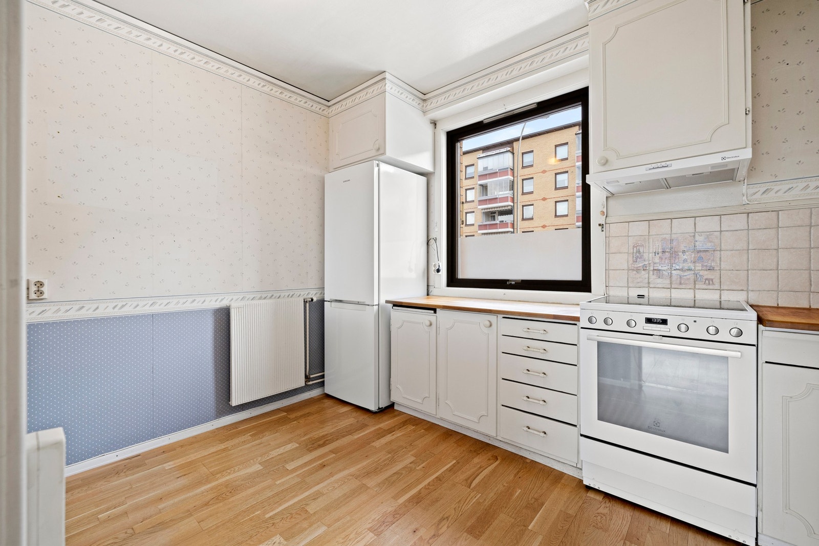 Kjøkkeninnredning med profilerte fronter og heltre benkeplate med frittstående hvitevarer. Galleribilde