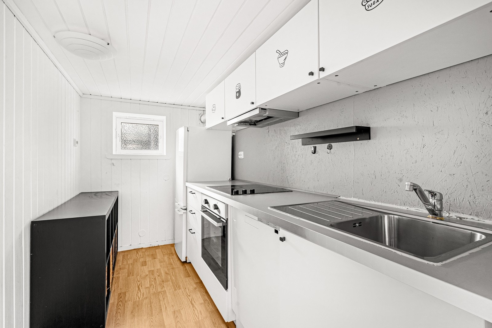 Kjøkkeninnredning fra 2020 med benkeplate av laminat og integrert stekeovn og platetopp. Frittstående oppvaskmaskin og kjøleskap. Galleribilde