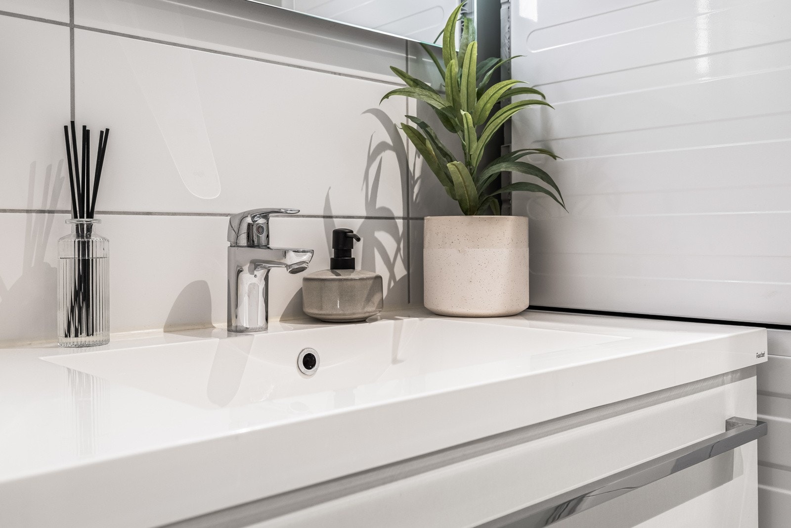 Baderommet inneholder servant med skuff, speil med belysning, veggmontert wc, dusjhjørne og opplegg for vaskemaskin/trommel. Galleribilde