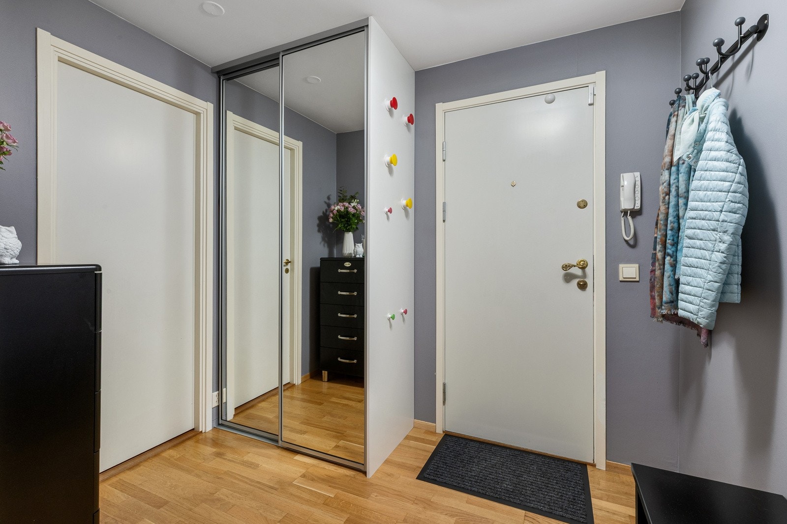 Entréen er romslig og innbydende, innredet med en praktisk garderobe med speildører som gir rikelig med oppbevaringsplass for yttertøy. Galleribilde