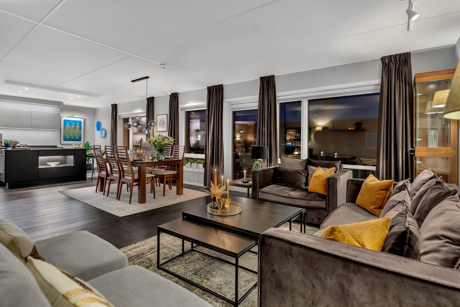 Kveldsstemning i stue. Leiligheten har lite innsyn. Plissegardiner i samtlige vinduer skjermer mot sol. Galleribilde