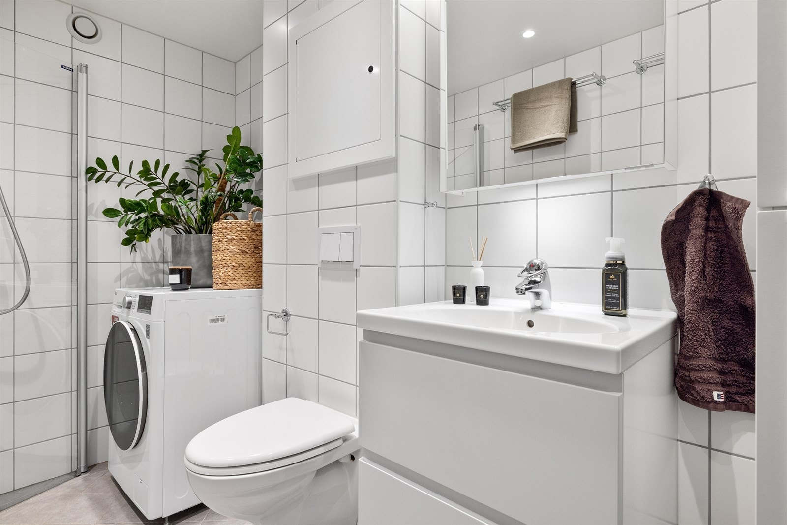 Vegghengt toalett og dusjhjørne med innfellbare glassdører. Baderomsinnredning, speilskap med belysning og høyskap Galleribilde