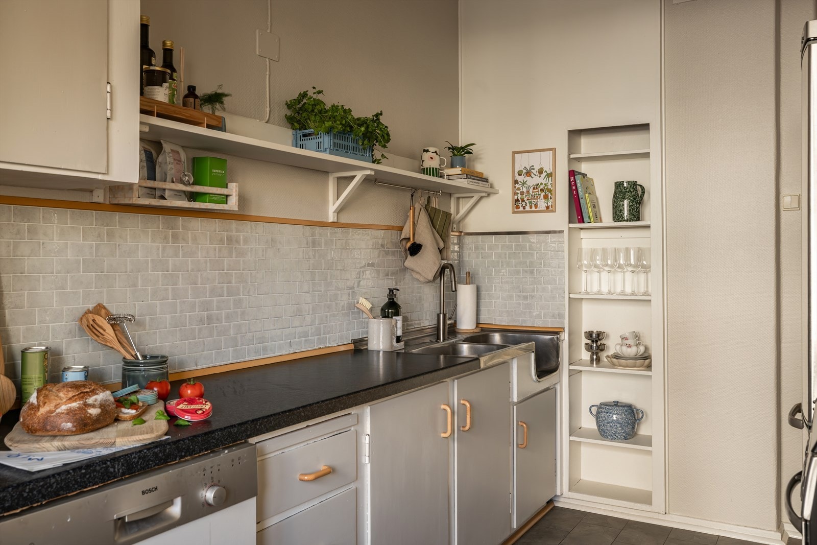 Kjøkkenet har laminert benkeplate med nedfelt dobbeltoppvaskkum med 1-greps blandebatteri, og fliser mellom over- og underskap. Galleribilde