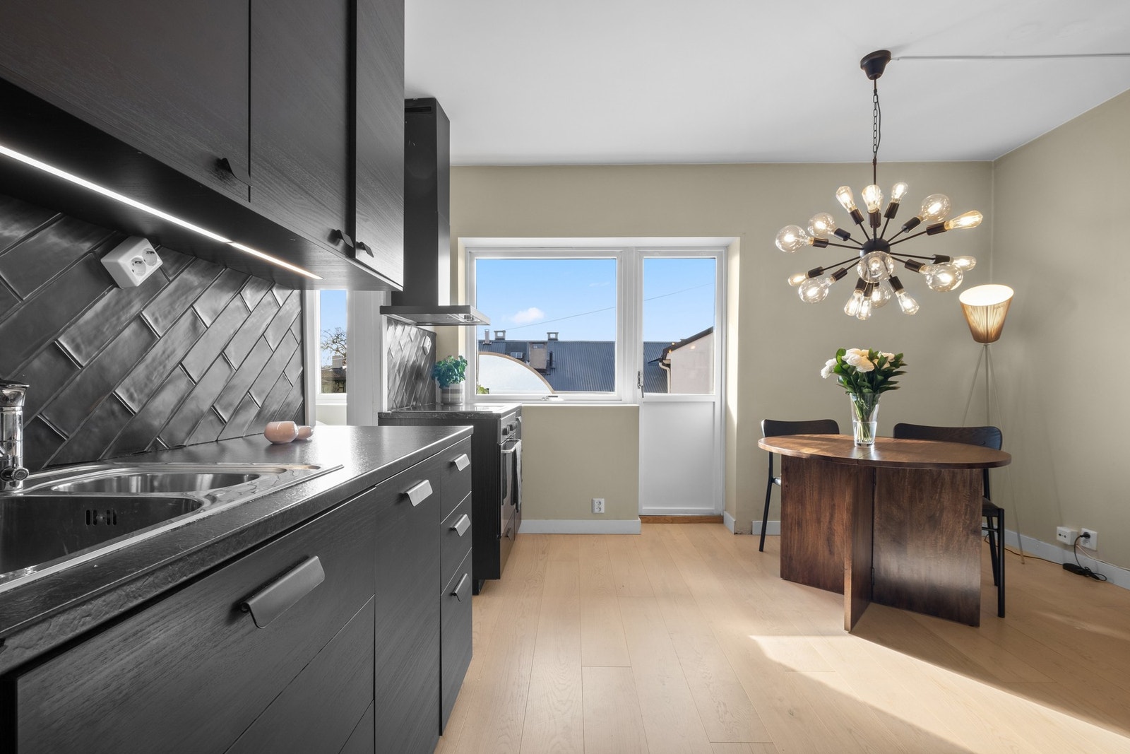 Kjøkkenet ble flyttet til stuen i 2018 og har en moderne innredning med glatte fronter i mørk utførelse, som står i fin kontrast til de beige veggene. Galleribilde