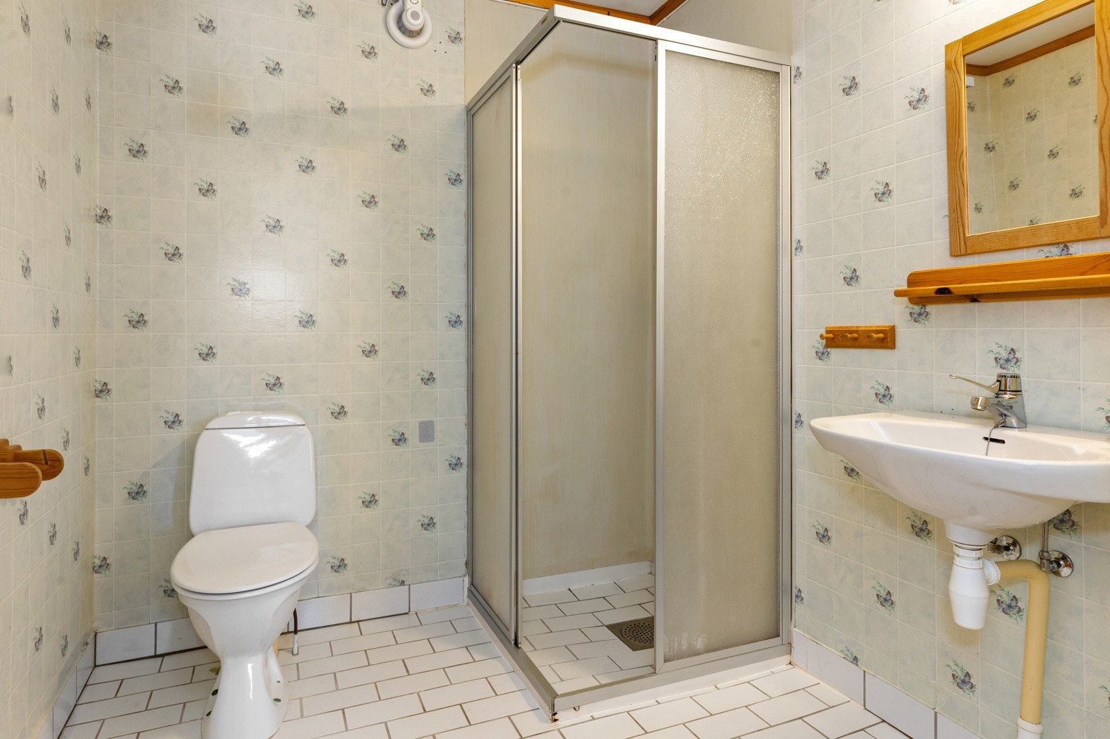 Bad i utleiedel fra 1989. Rommet har servant, gulvfestet toalett og dusjhjørne. Galleribilde