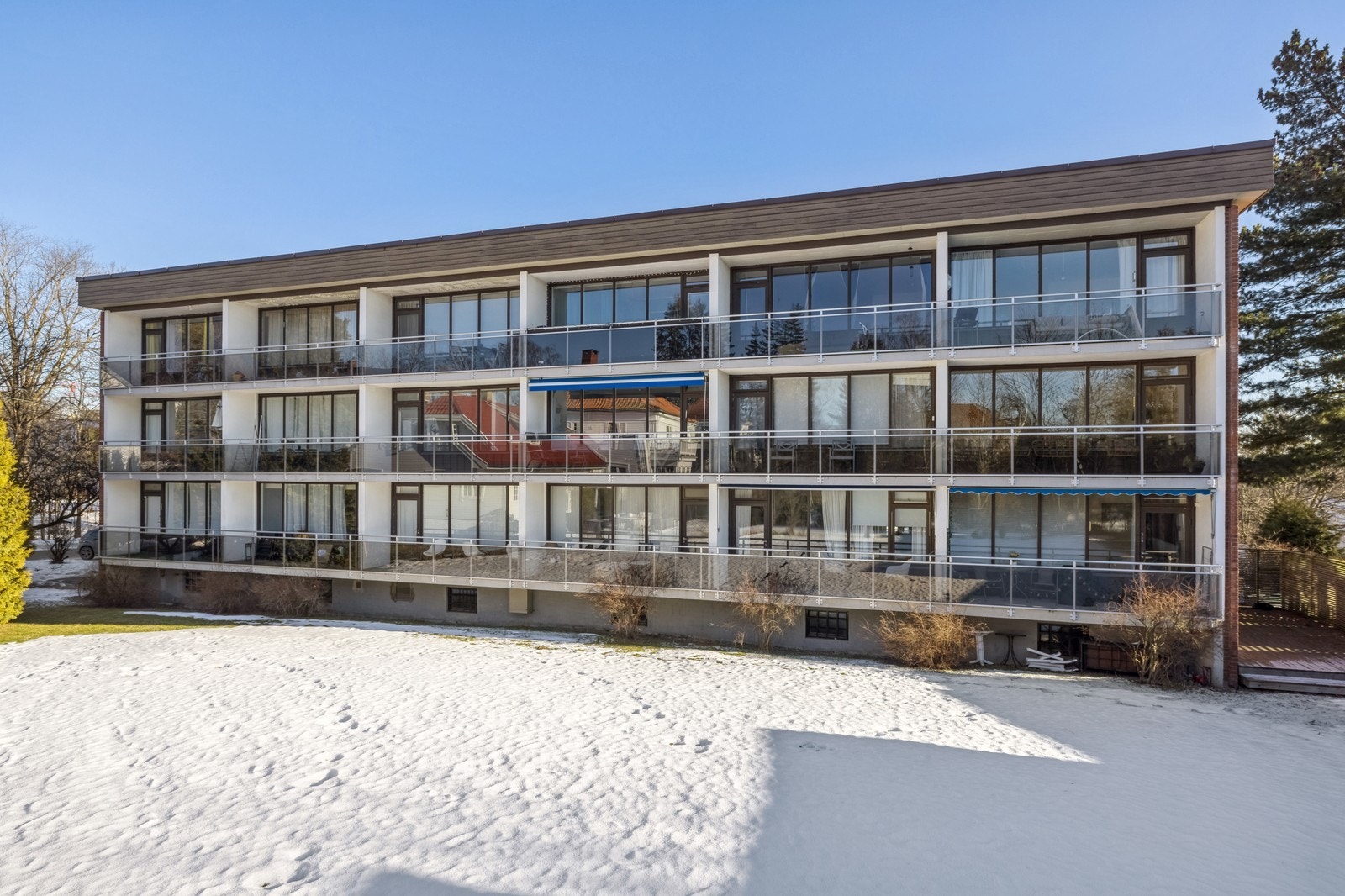 Bygg med store glassvinduer og balkonger i rolig område. Galleribilde