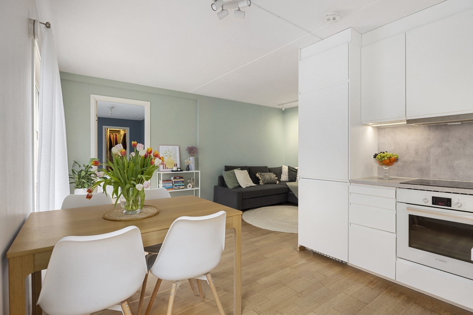 Ny kjøkkeninnredning i 2021. Slette, hvite fronter med integrerte håndtak. Benkeplater i laminat og belysning under overskap Galleribilde